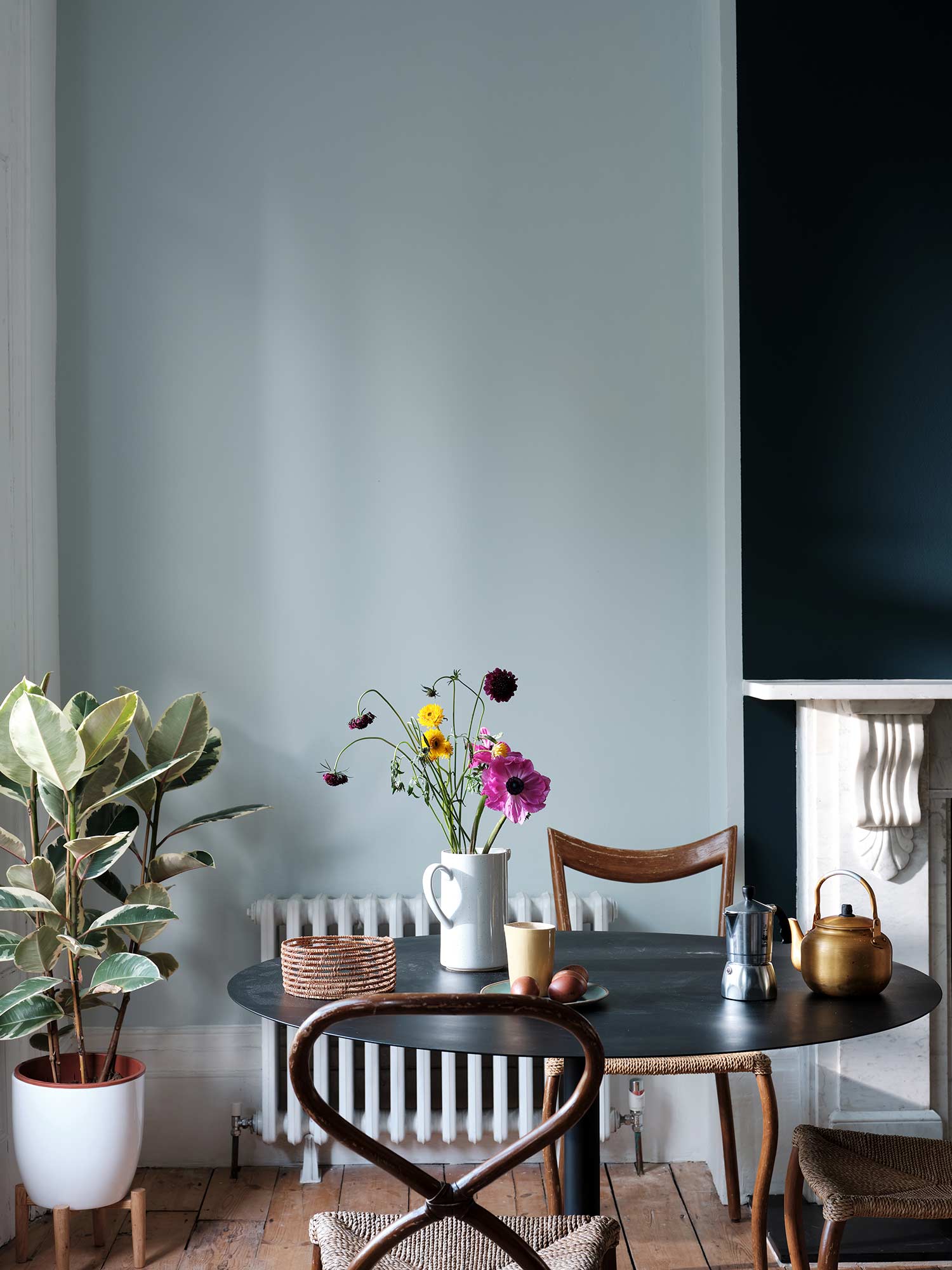 Esszimmer mit Borrowed Light No. 235 von Farrow & Ball. Zartes Hellblau an den Wänden mit schwarzem Rundtisch und Holzstühlen.