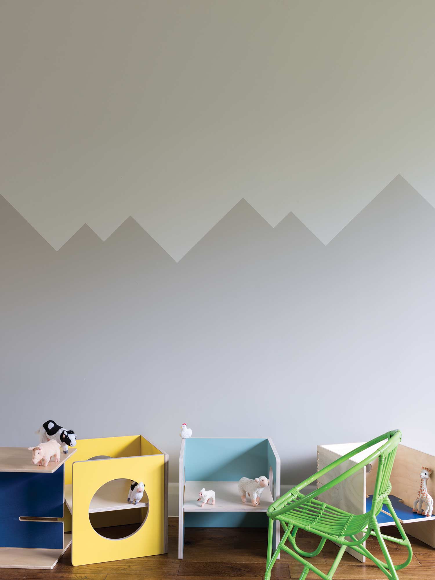 Kinderzimmer mit Ammonite No. 274 oben und Purbeck Stone No. 275 unten von Farrow & Ball. Ruhige Grautöne an der Wand mit bunten Spielzeugkisten.