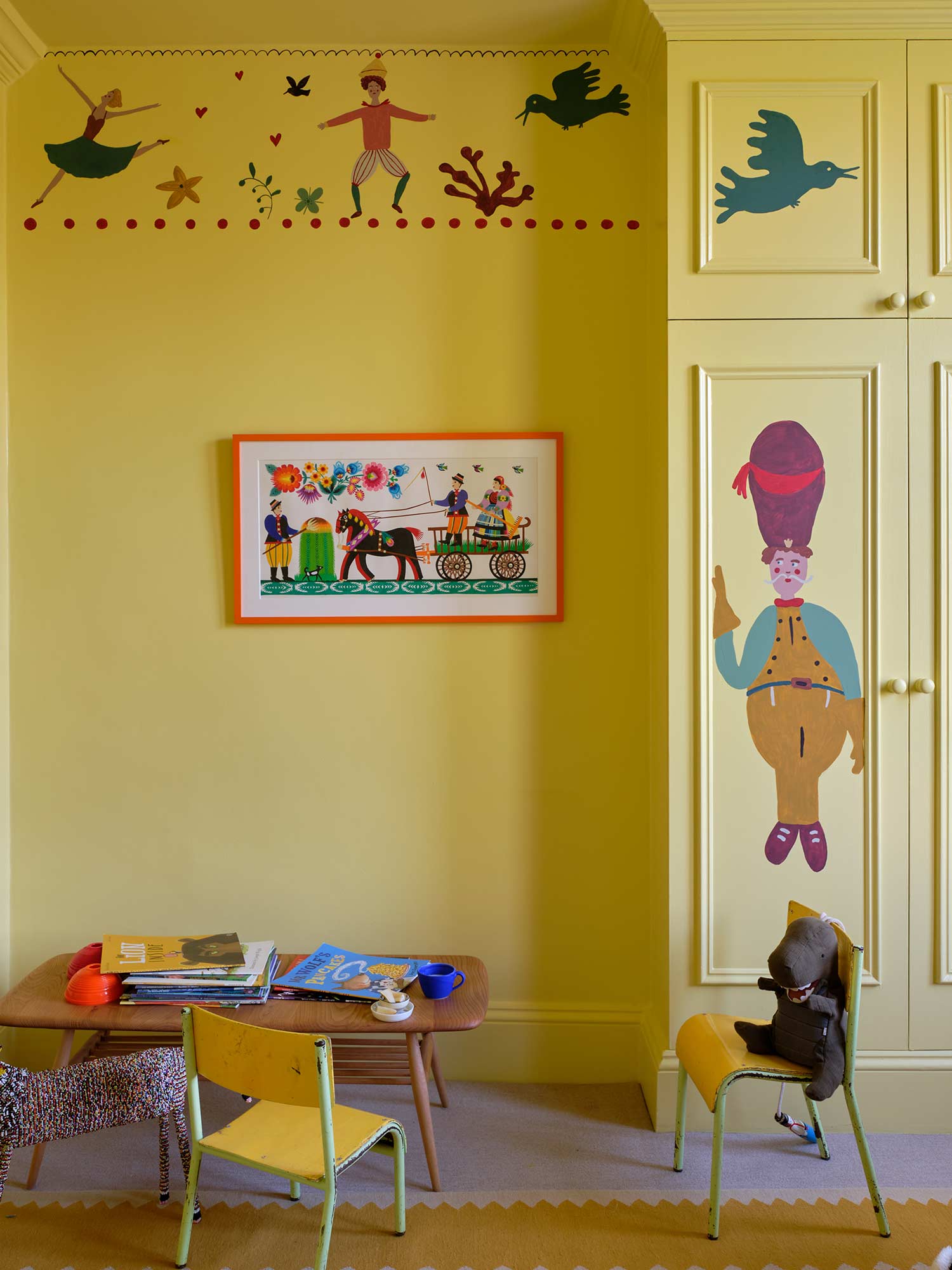 Kinderzimmer mit Dayroom Yellow No. 233 von Farrow & Ball. Frisches helles Gelb an Wänden und Schrank mit farbenfrohen Figuren und Girlanden.