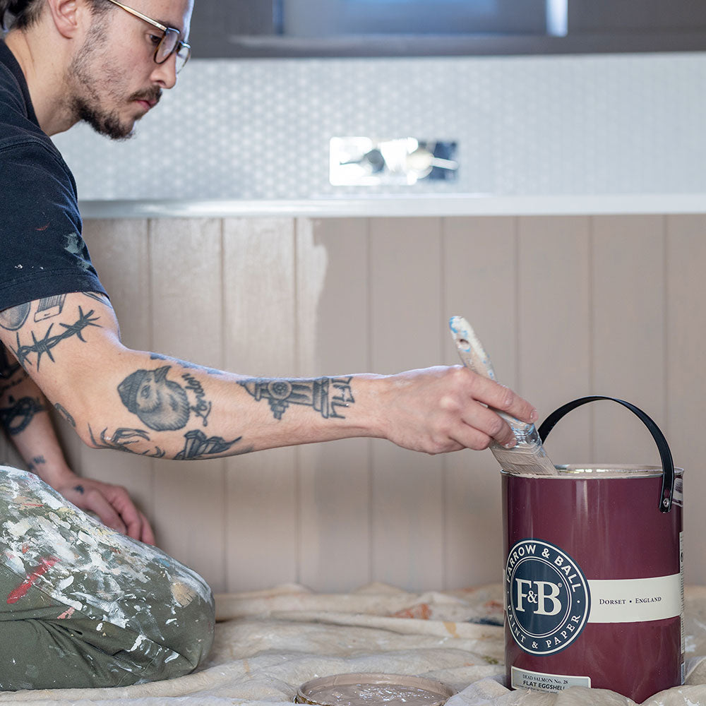 Ein Maler der mit Farrow and Ball Farben eine Wand streicht
